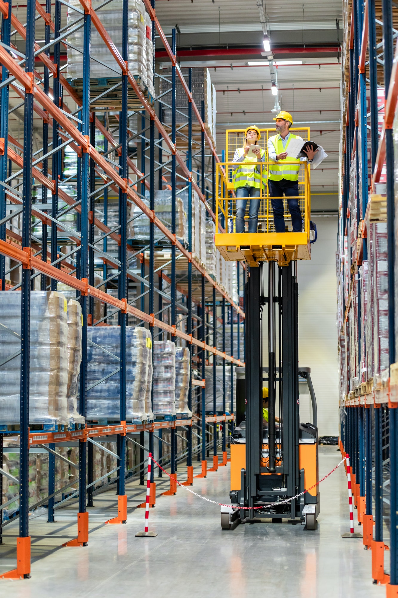 Warehouse workers on the height using lift work platform to check inventory